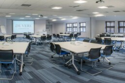 A meeting room with multiple tables that have water and paper on them