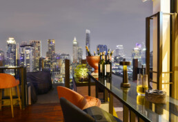 a rooftop bar in an evening setting with wine on the table