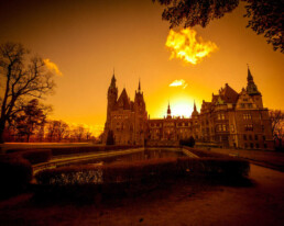 A sunset with a large country house in it